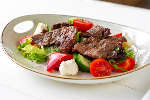 Filetto di manzo con insalata di verdure su tavola di legno