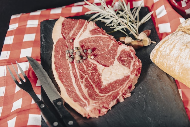 Filetto di manzo crudo mignon con rosmarino, pepe e sale su tavola rustica scura, carne di black angus.