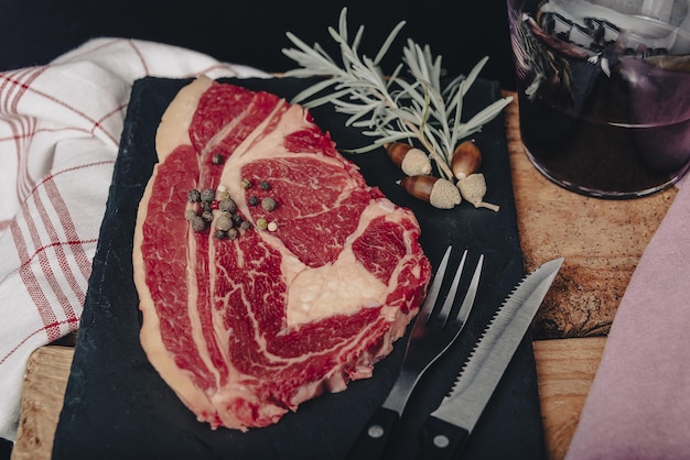 Filetto di manzo crudo mignon con rosmarino, pepe e sale su tavola rustica scura, carne di black angus.