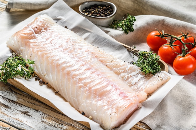 Filetto di merluzzo crudo ed erbe sul tagliere di legno