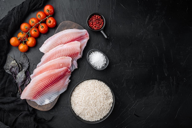 Filetto di pesce bianco, con ingredienti di riso basmati e pomodorini, sulla tavola nera, vista dall'alto