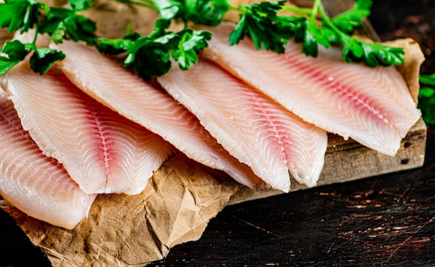 Filetto di pesce crudo su vassoio di legno con prezzemolo