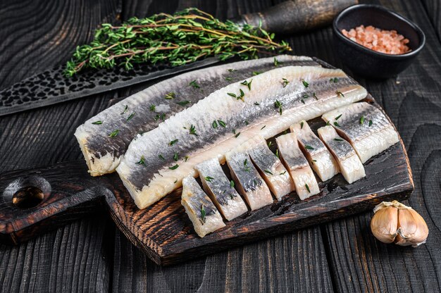 Filetto di pesce di aringa salata a fette su una tavola di legno.