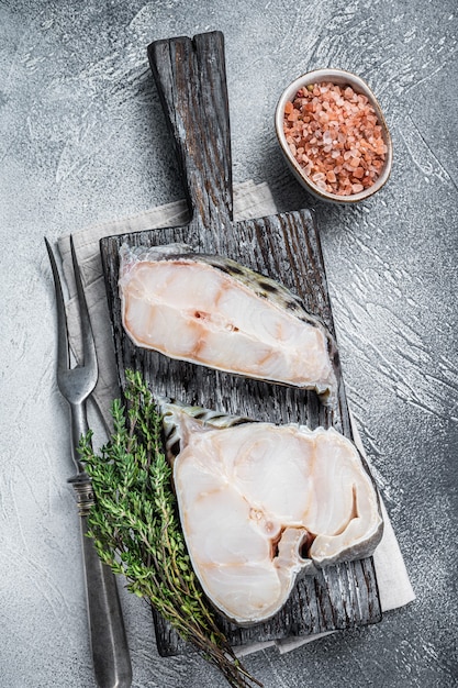 Filetto di pesce lupo crudo Bistecca di pesce sul tagliere di legno. Sfondo bianco. Vista dall'alto.