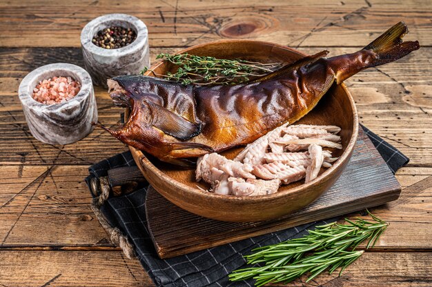 Filetto di pesce persico affumicato caldo o lucioperca in un piatto di legno con erbe aromatiche. fondo in legno. Vista dall'alto.