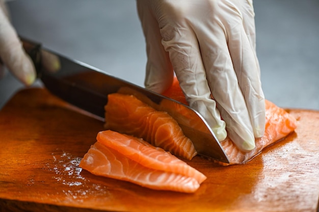 Filetto di pesce salmone crudo fresco con coltello da cucina per cucinare cibo pesce salmone filetto di salmone sul tagliere di legno