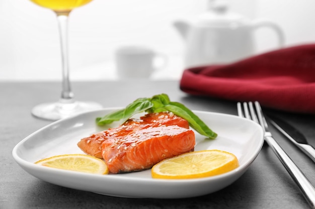 Filetto di pesce servito con fettine di limone e foglie di basilico fresco sul tavolo della cucina