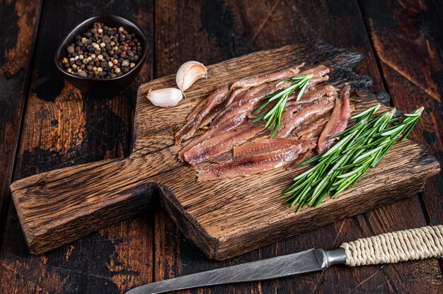 Filetto di pesce sott'aceto di acciughe su una tavola di legno. Fondo in legno scuro. Vista dall'alto.