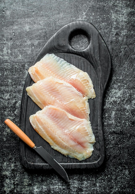 Filetto di pesce su un tagliere con un coltello