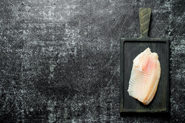 Filetto di pesce su un tagliere nero