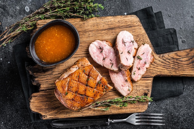 Filetto di petto d'anatra a fette, bistecca arrosto con salsa. Sfondo nero. Vista dall'alto.