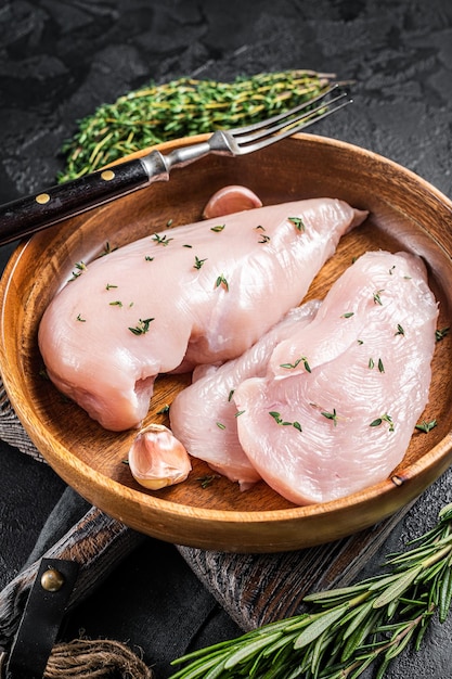 Filetto di petto di pollo crudo a fette Bistecche di carne di pollame in piastra Sfondo nero Vista dall'alto