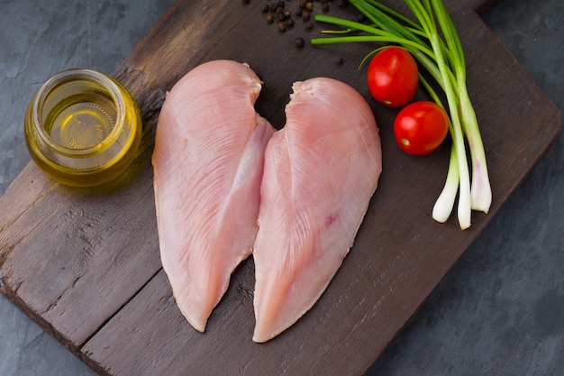 Filetto di petto di pollo crudo fresco senza pelle disposto su una tavola di legno