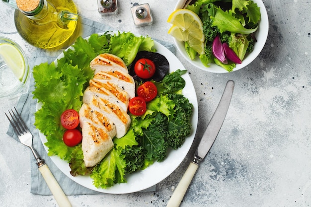 Filetto di petto di pollo e insalata di verdure con pomodori e foglie verdi su sfondo chiaro Il concetto di cibo sano e dieta cheto Vista dall'alto con spazio di copia