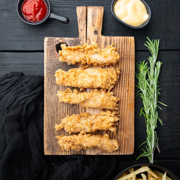 Filetto di petto di pollo impanato su fondo di legno nero, piatto disteso.