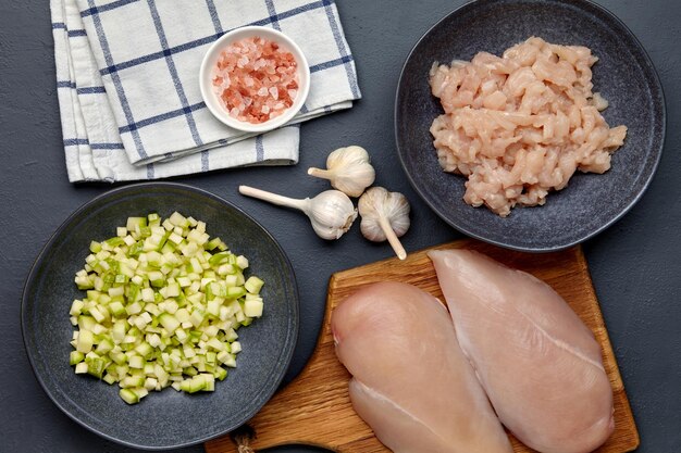 Filetto di petto di pollo tritato tritato su un tagliere e in una ciotola zucchine tritate