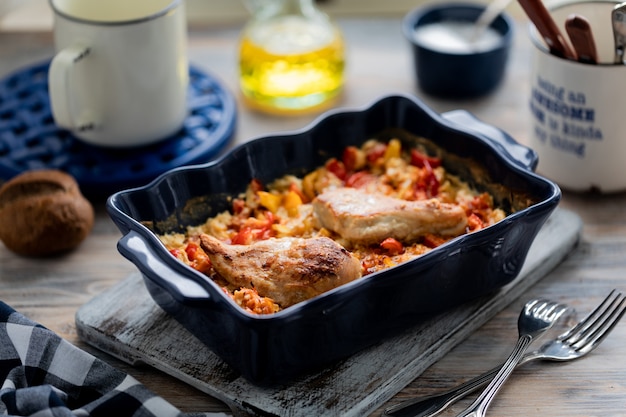 Filetto di pollo al forno con peperoni in un piatto di ceramica blu su un tavolo di legno