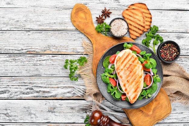 Filetto di pollo al forno con verdure In un piatto nero su sfondo di legno Vista dall'alto Spazio libero per il testo Disposizione piatta