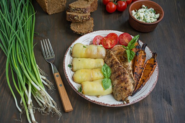 Filetto di pollo alla griglia con verdure al forno, involtini di peperone. Di legno.