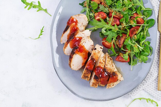 Filetto di pollo arrosto con insalata di pomodori freschi e rucola. Vista dall'alto, posizione piatta