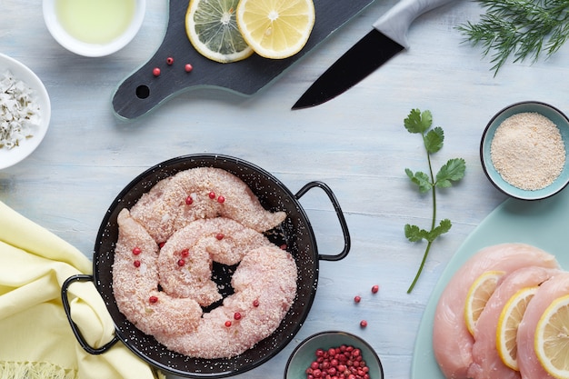 Filetto di pollo crudo. Carne con pangrattato, erbe aromatiche, limone e olio da cucina, copia-spazio