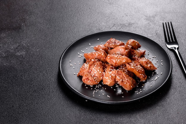 Filetto di pollo in semi di sesamo, salsa teriyaki su un piatto di pietra nera. Cucina asiatica