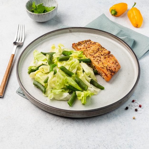 Filetto di salmone alla griglia con fagiolini e foglie di lattuga su un piatto