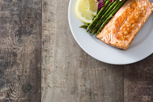 Filetto di salmone arrostito con asparagi e insalata sullo spazio di legno della copia di vista del piano d'appoggio