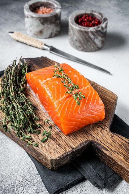 Filetto di salmone crudo fresco su tavola di legno. Sfondo bianco. Vista dall'alto.