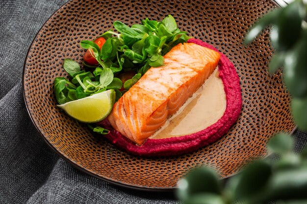 Filetto di salmone di pesce fritto con contorno di humus rosa.