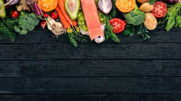 Filetto di salmone e verdure fresche Cibo sano Su uno sfondo di legno nero Cibo sano Vista dall'alto Spazio di copia