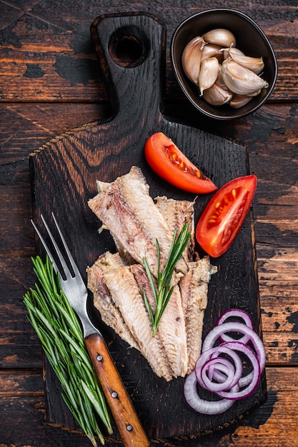 Filetto di sardina affumicata su tavola di legno con erbe aromatiche