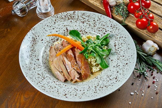 Filetto di tacchino arrosto con bulgur e spinaci in un piatto di ceramica beige su un tavolo di legno. Nutrizione per il fitness. Cibo salutare. Vista da vicino