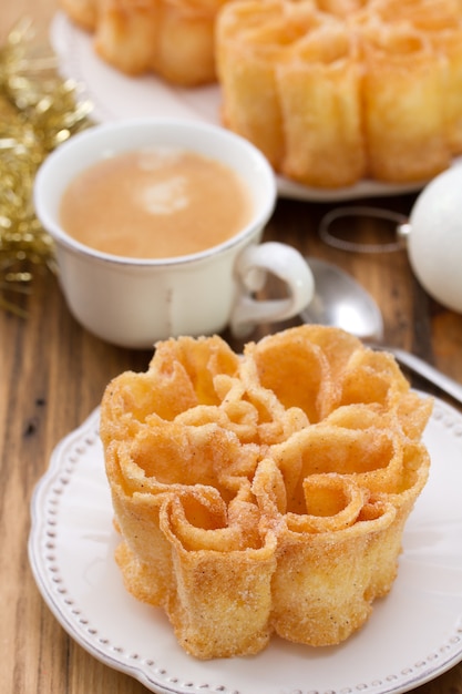 Filhos portoghesi tipici del dessert sul piatto bianco su superficie e su caffè di legno marroni