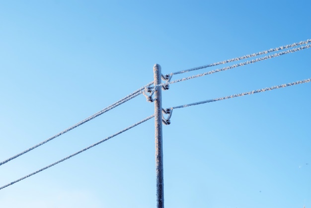 Fili ghiacciati nel gelo sulla linea elettrica contro il cielo invernale blu