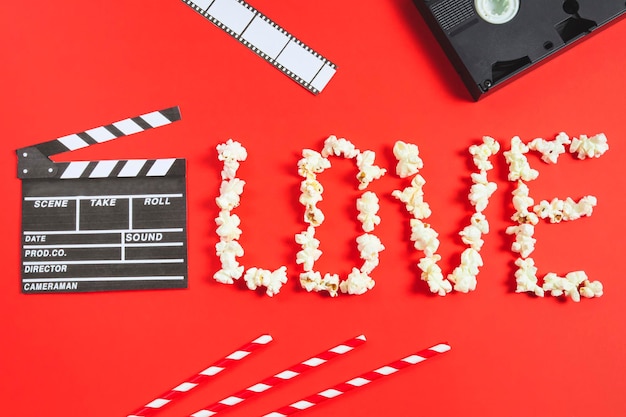 Film ciak film strip videocassette cannucce e la parola amore da popcorn giacciono su un rosso