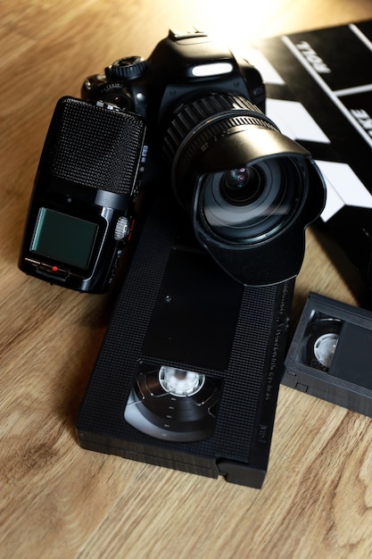 Film clapper con una telecamera, un microfono e un nastro VHS su legno.