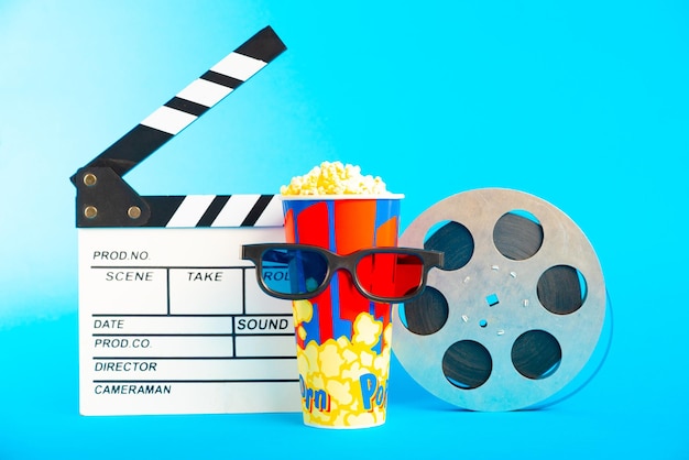Film clapper pop corn occhiali 3D e bobina di film su sfondo blu disegno di collage