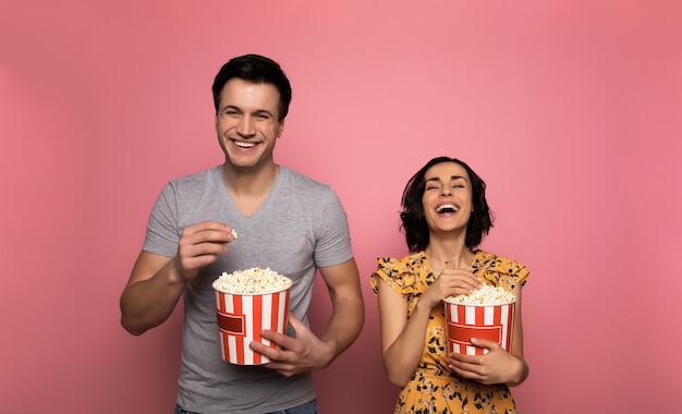 Film divertente. felice giovane coppia, che stanno mangiando popcorn e ridendo insieme mentre guardano film.