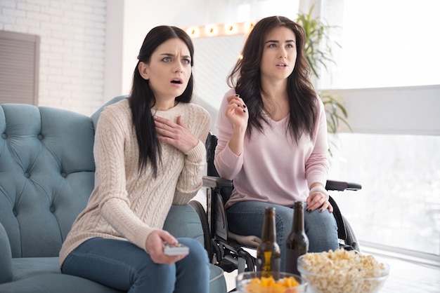 Film spaventoso. Sorella spaventata e donna disabile guardando film e aprendo la bocca