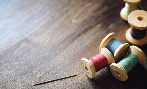 Filo per cucire su un fondo di legno. Set di fili su bobine in stile retrò. Accessori vintage per cucire in tavola