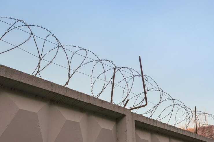 Filo spinato sullo sfondo di un cielo libero Recinzione in cemento con filo affilato