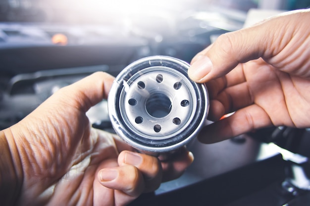 Filtro dell'olio nella mano del meccanico per la manutenzione del sistema dell'olio motore nell'officina di riparazione