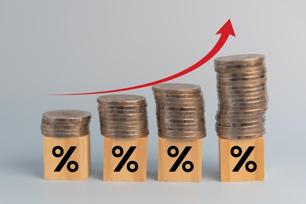 Finanza aziendale investimenti economia pila moneta inflazione e freccia rossa con percentuale di cubo di legno sulla scrivania