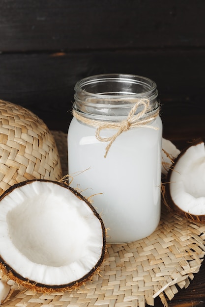 Fine del barattolo di vetro del latte di cocco su su fondo di legno