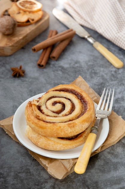 Fine del panino del rotolo di cannella su. Pasticceria di turbinio di cannella per la prima colazione su gray