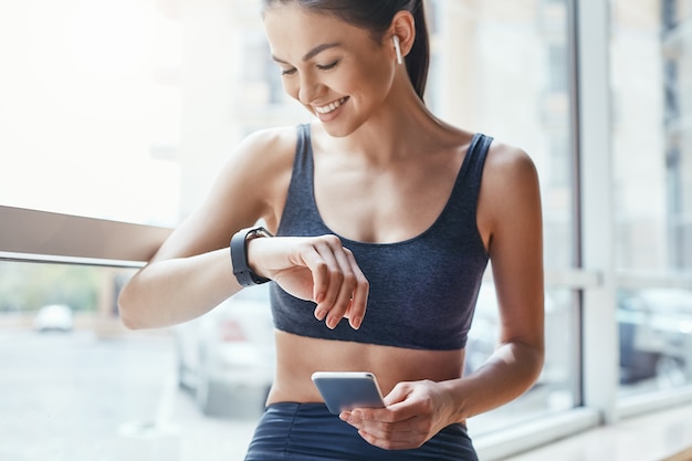 Fine dell'allenamento vista posteriore di una giovane donna bassa e magra in abiti sportivi in piedi in palestra