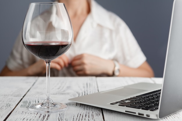 Fine della donna di opere con bicchiere di vino rosso tablet e laptop