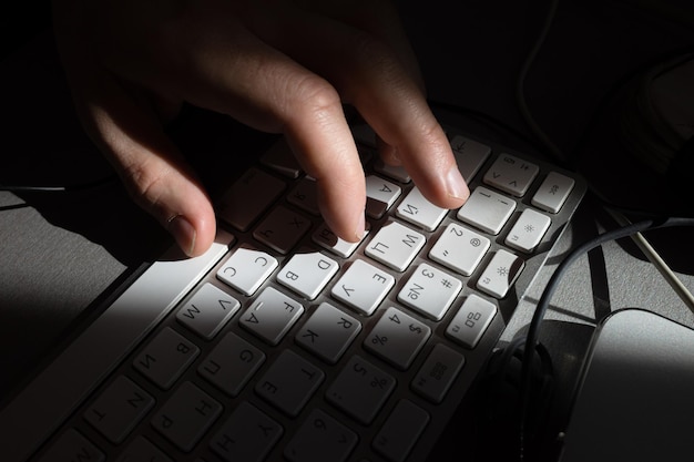 Fine della tastiera del computer e della mano. Uomo che lavora a casa ufficio mano sulla tastiera si chiuda. Messa a fuoco selettiva.