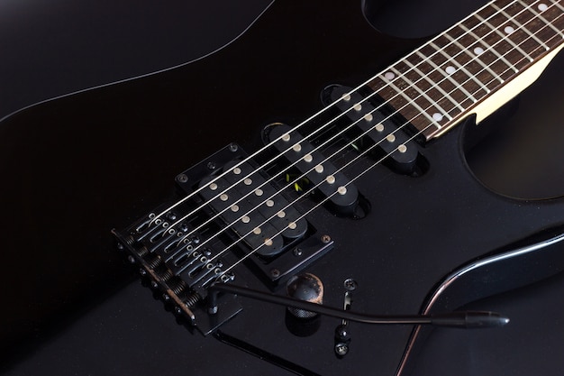Fine nera della chitarra elettrica su su fondo scuro.